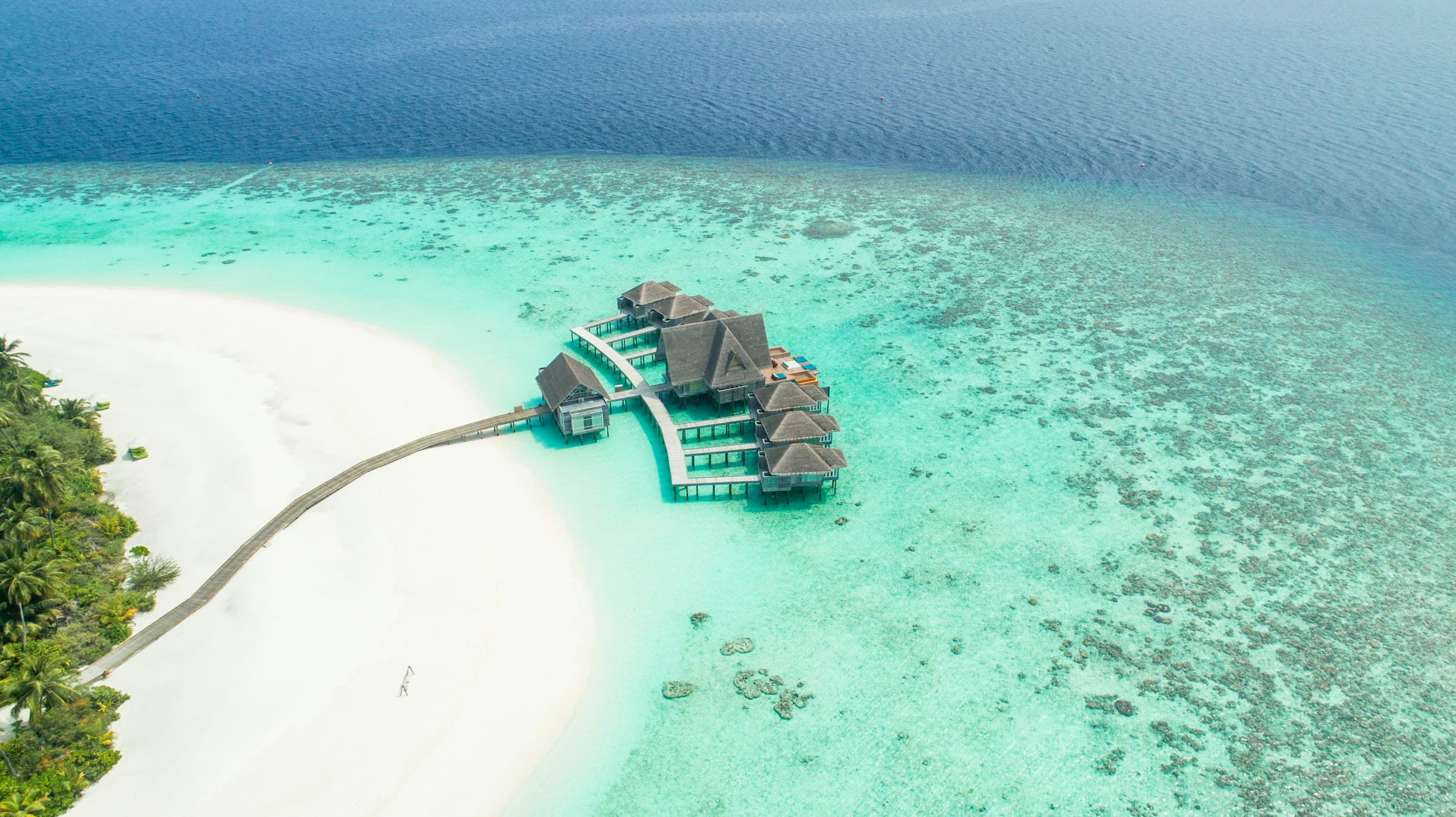 An aerial view of an island resort surrounded by turquoise water